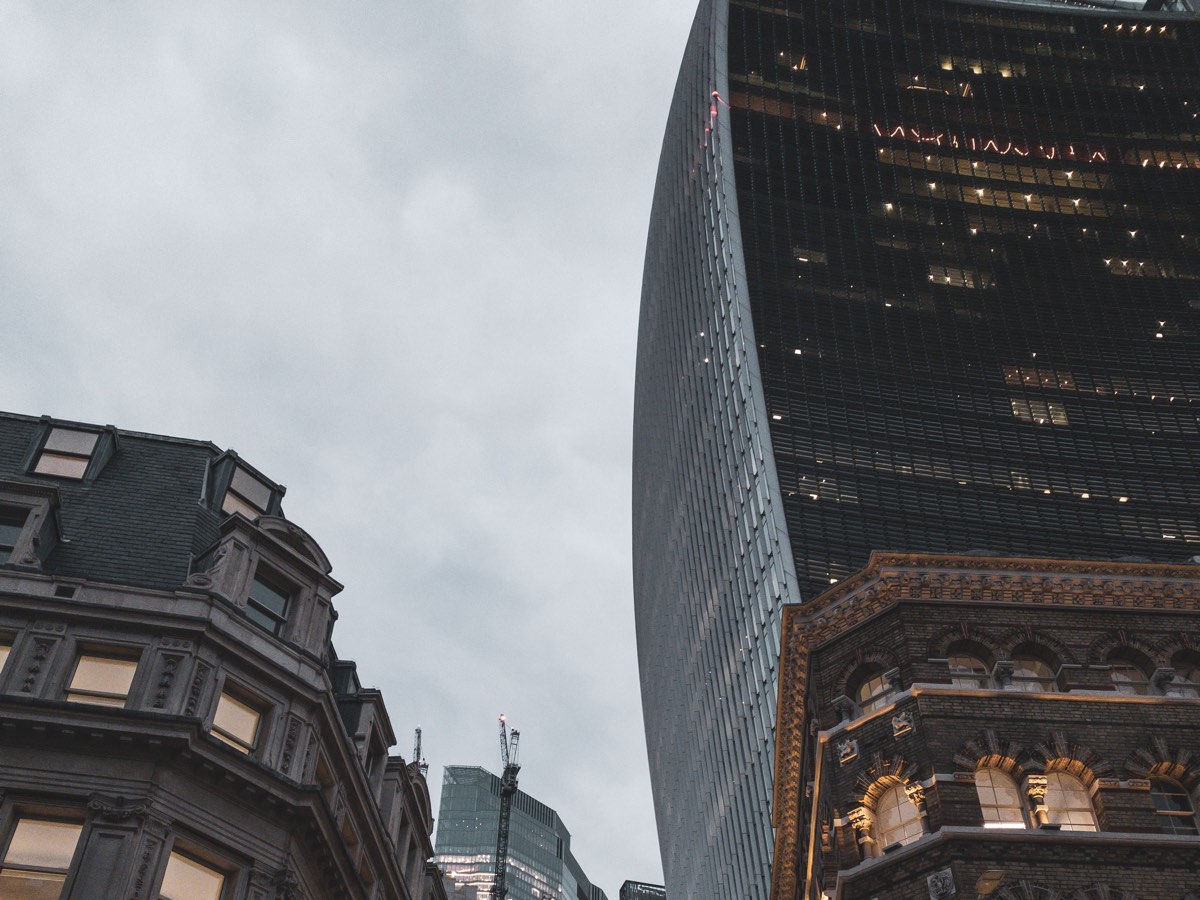 Towers of the City of London rising above Victorian stone frontages at dusk.