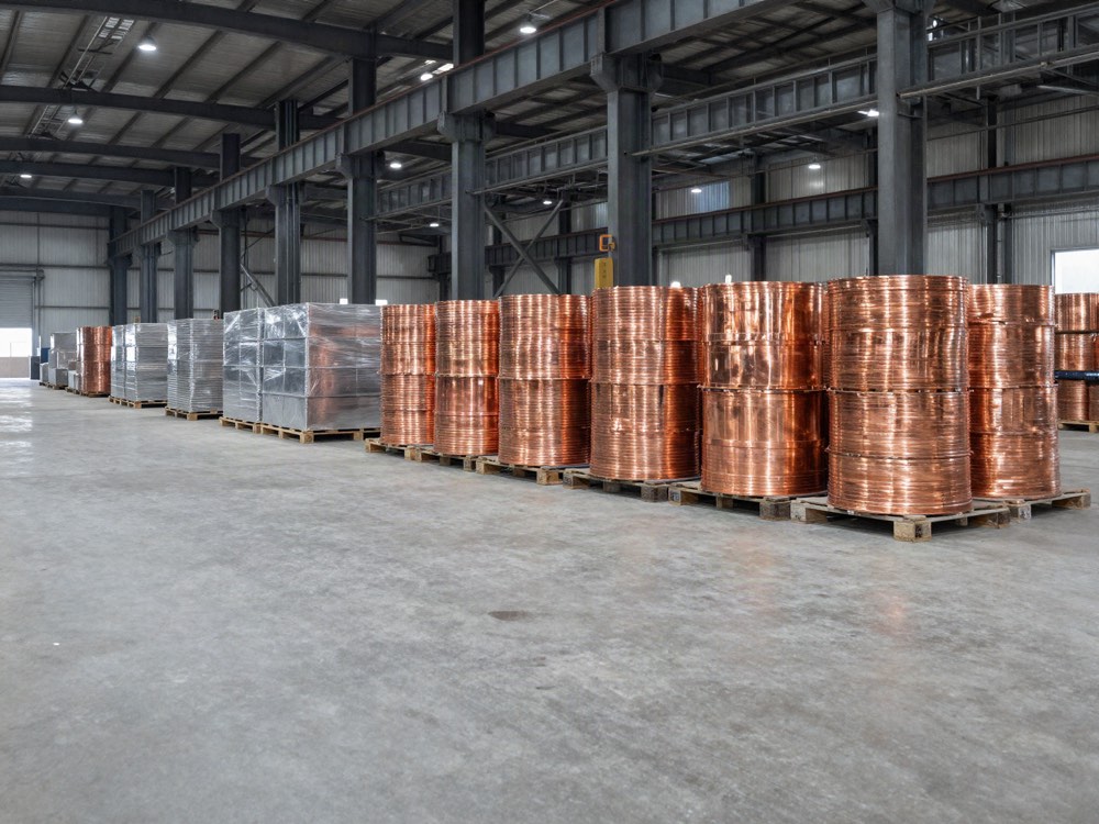Pallets of copper wire rod coils stored in an industrial metals warehouse.
