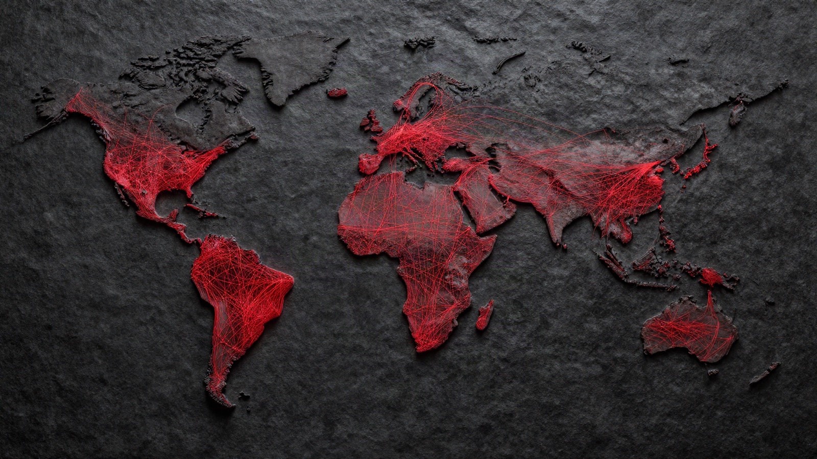 A world map carved in dark slate, its continents overlaid with a dense web of fine red trade routes reaching across Africa, South America, Asia and Europe.